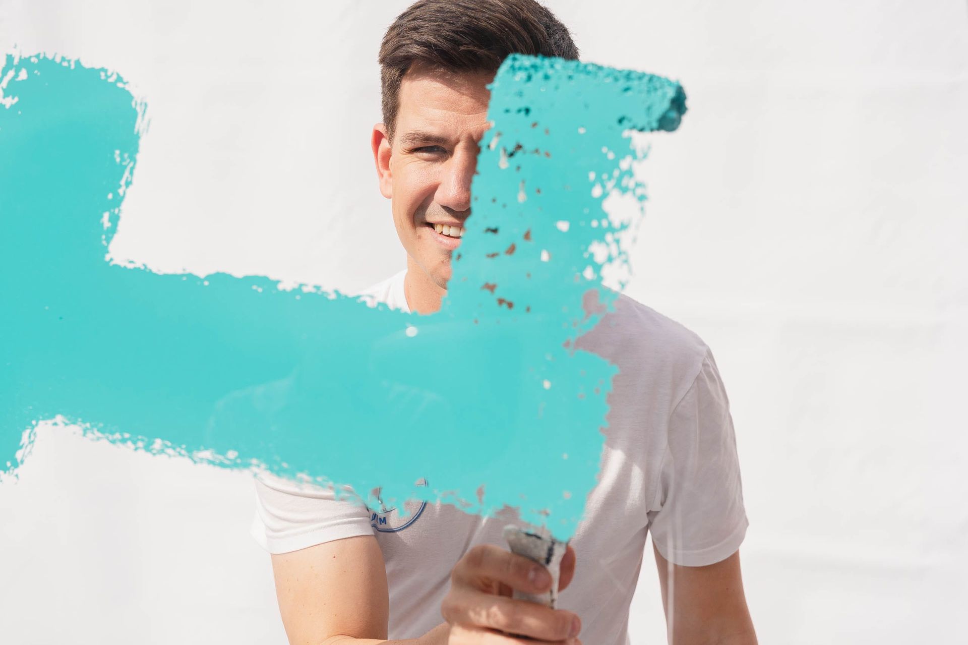 Mann streicht mit blauer Farbe an einer Wand