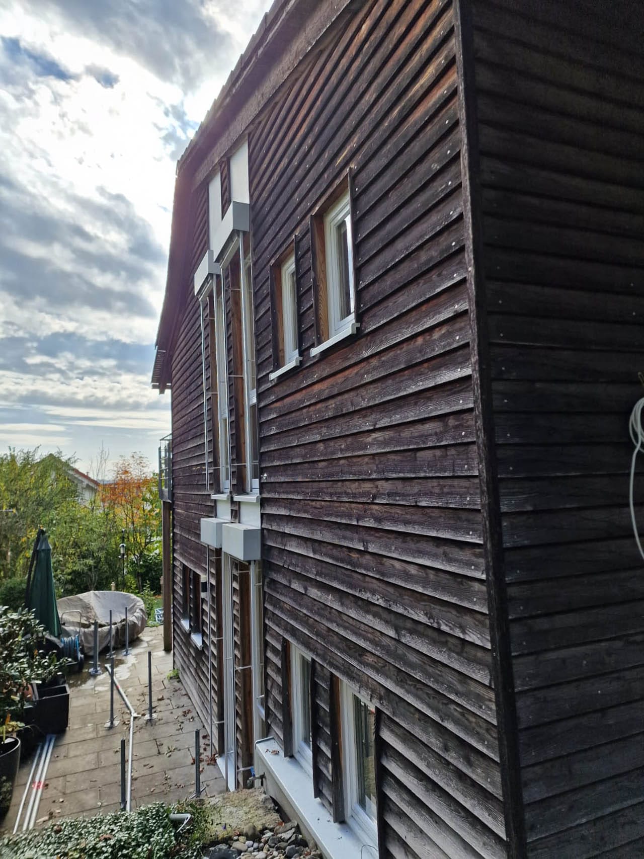Holzhaus mit Fenstern und Gartenbereich.