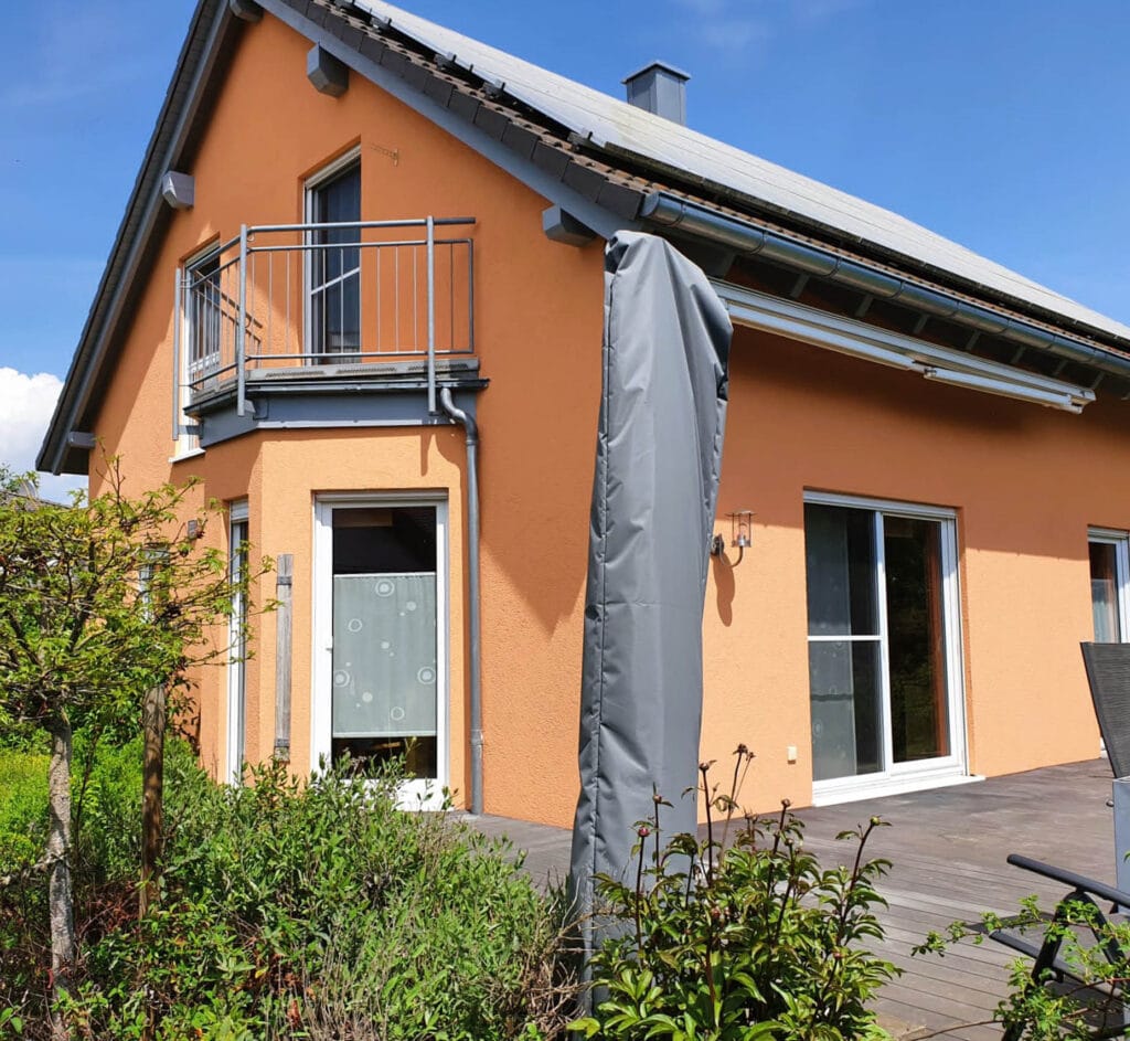 Modernes orangefarbenes Haus mit Balkon und Garten