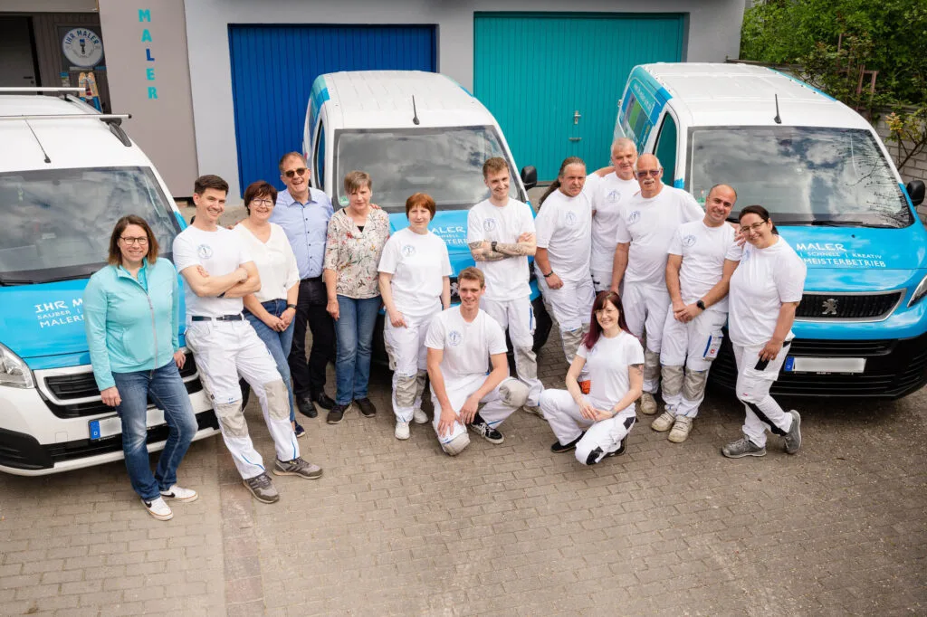 Malerteam vor den Firmenfahrzeugen.