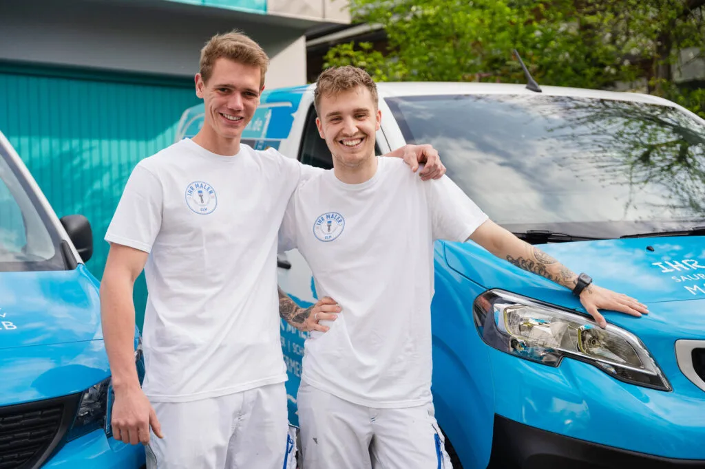 Zwei junge Männer vor einem blauen Lieferwagen