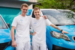 Zwei junge Männer vor einem blauen Lieferwagen