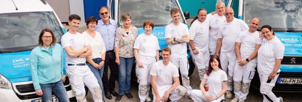 Teamfoto einer Malerfirma vor ihren Fahrzeugen.