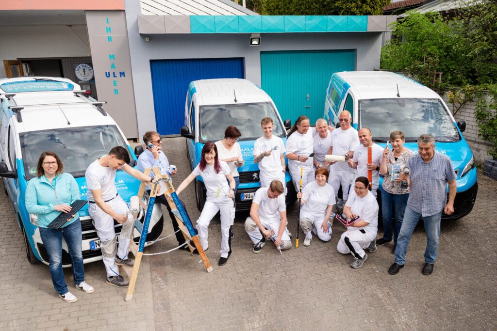 Malerteam vor Fahrzeugen in der Werkstatt.