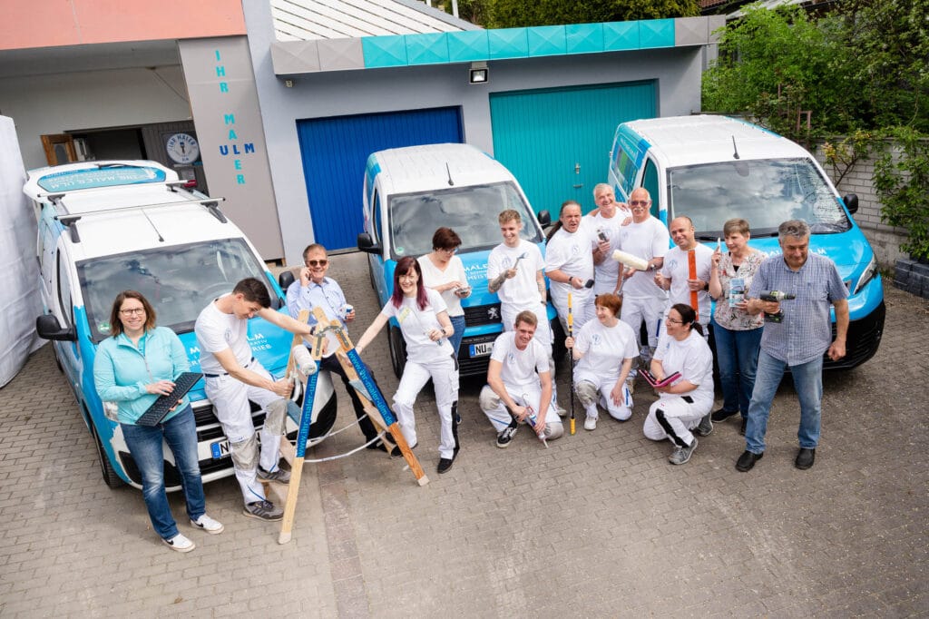 Malerteam bei der Arbeit vor ihren Fahrzeugen