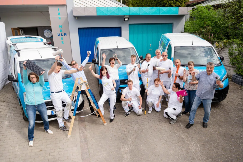 Teamfoto von Malern vor ihren Fahrzeugen.
