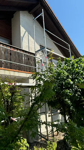 Haus mit Gerüst und grünem Pflanzenbewuchs