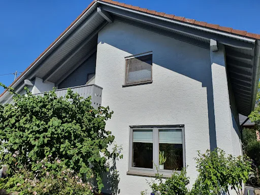 Helles Haus mit Pflanzen im Vordergrund.